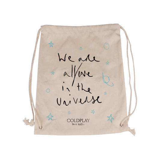 We are all/one in the Universe in Chris’ handwriting on the front of a hemp bag with light blue hand drawn stars, circles, and planets surrounding the text. Coldplay logo and handwritten Moon Music are smaller, centered at the bottom in black.