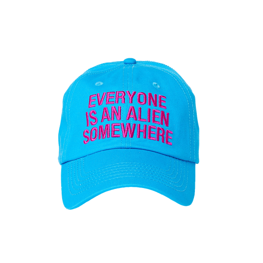 Bright blue baseball hat, with EVERYONE IS AN ALIEN SOMEWHERE embroidered on the front, in dark pink fuchsia. The font is bold.